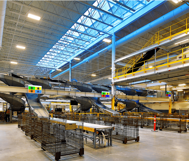 Le vaste intérieur du Centre de traitement Albert-Jackson, rempli d’imposantes machines à trier le courrier. Les puits de lumière au plafond laissent entrer beaucoup de lumière naturelle.