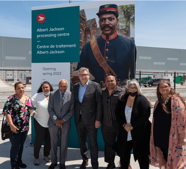 Canada Post President and CEO Doug Ettinger and members of Albert Jackson's family pose together at the official naming ceremony at the site of the Albert Jackson Processing Centre.