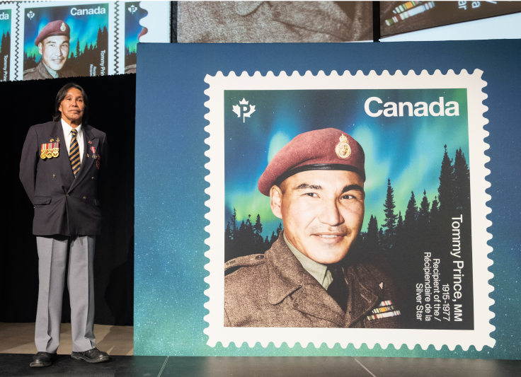 Tommy Prince fils se tient à côté d’un agrandissement du timbre commémoratif célébrant l’héritage de son père, Tommy Prince, durant une cérémonie organisée au Musée canadien pour les droits de la personne de Winnipeg, où la vignette a été dévoilée en octobre 2022