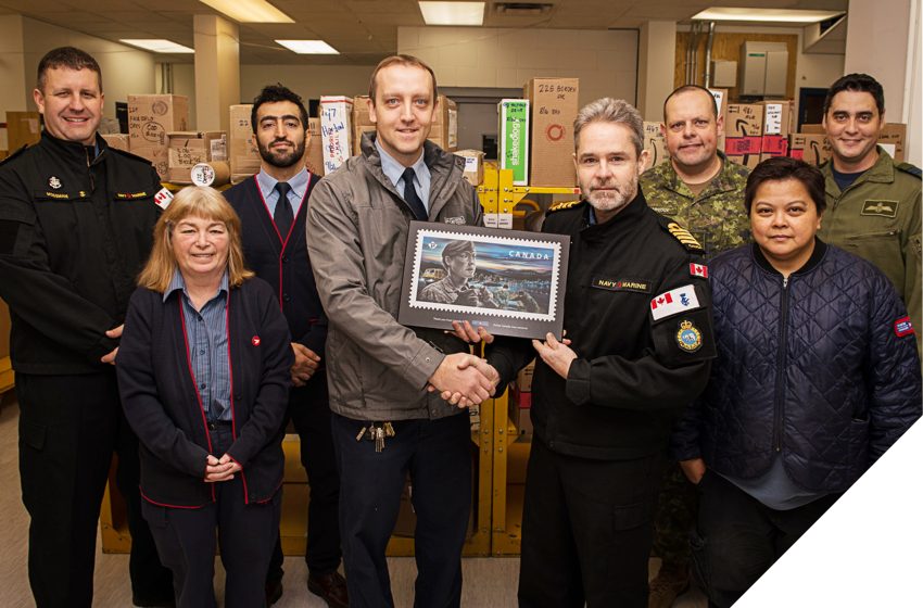 Canadian Armed Forces personnel in Yellowknife, N.W.T. accept a stamp plaque saluting CAF members.
