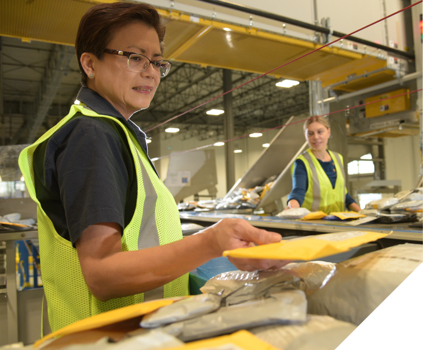Two female Canada Post employees sorting through parcels and envelopes