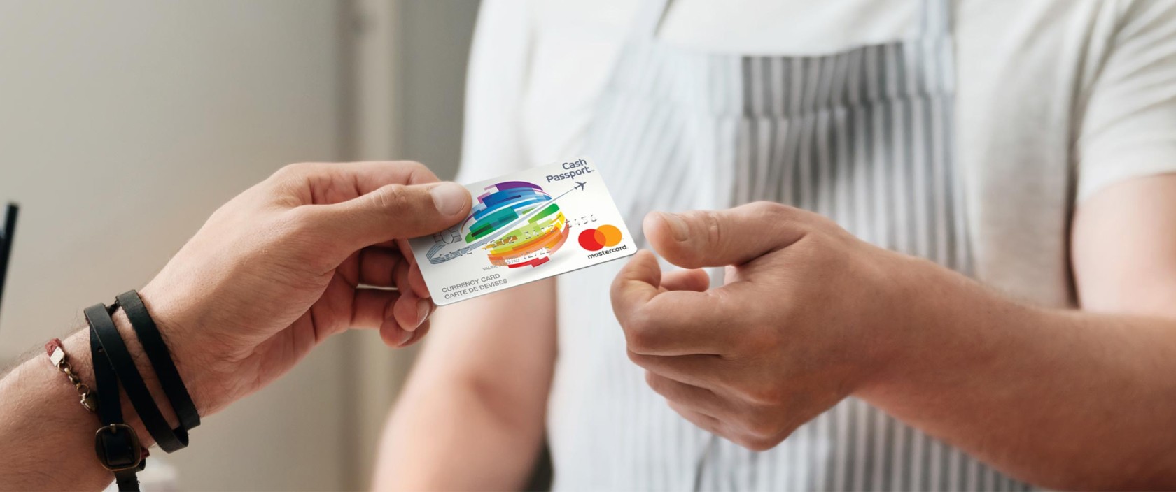 A man hands a Canada Post Cash Passport Prepaid Mastercard to a cashier.