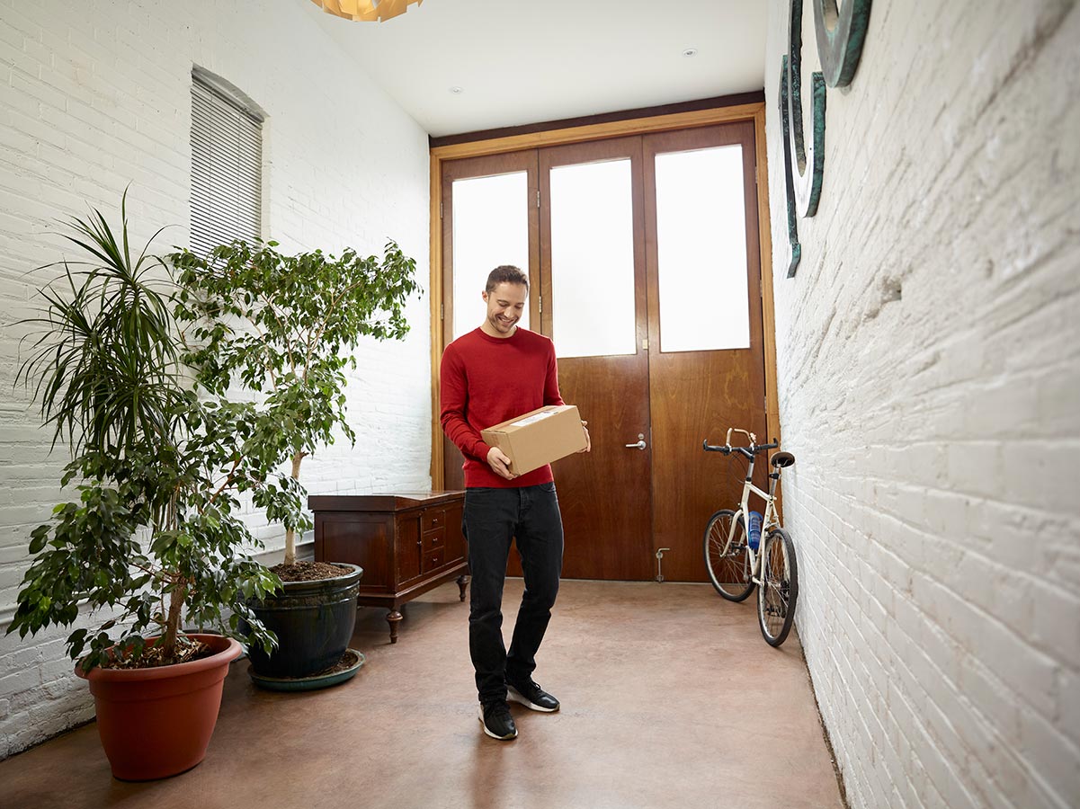 Man in a front hallway holding a package he just received