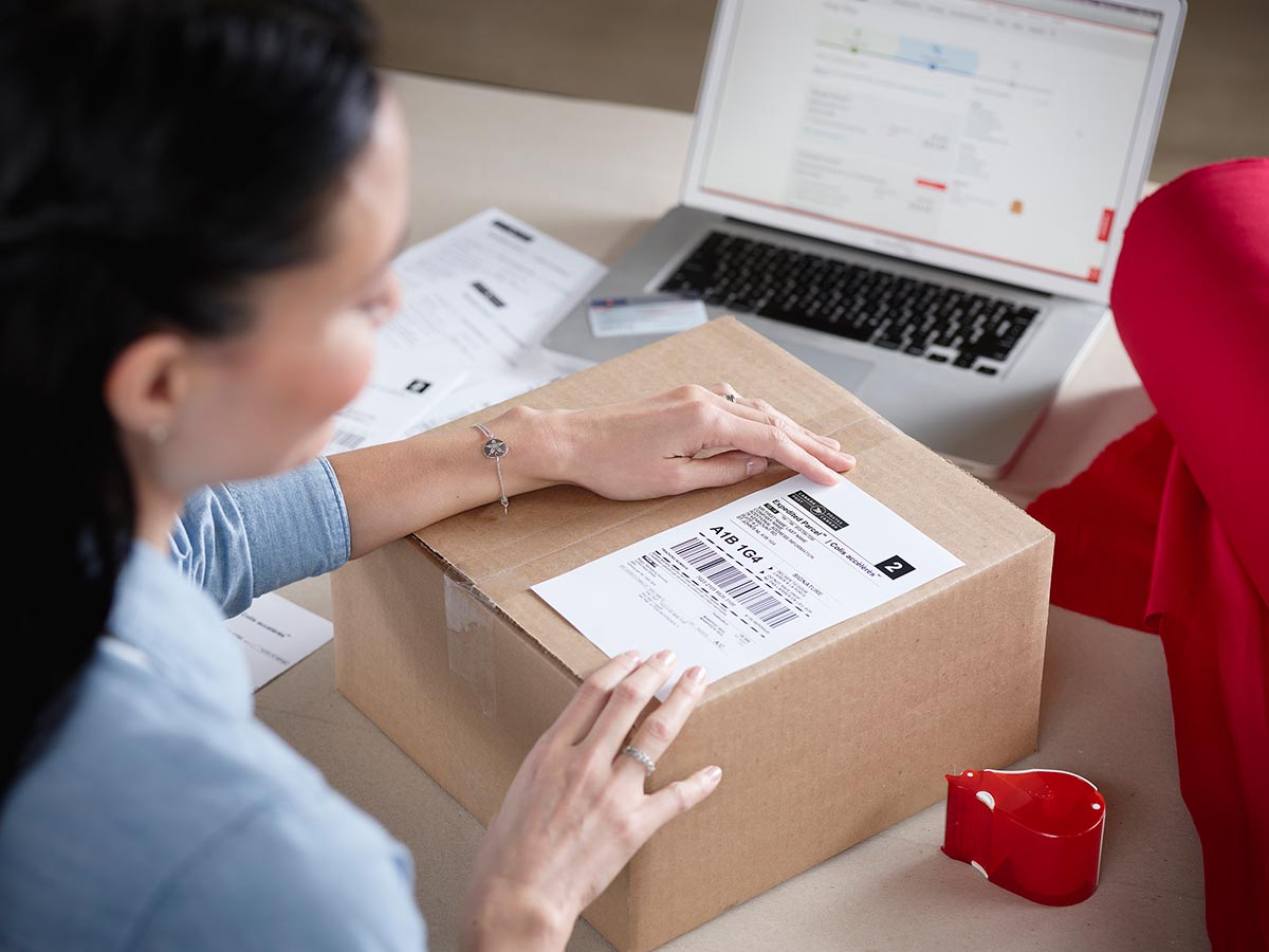 Woman at a desk applying a shipping label to a package