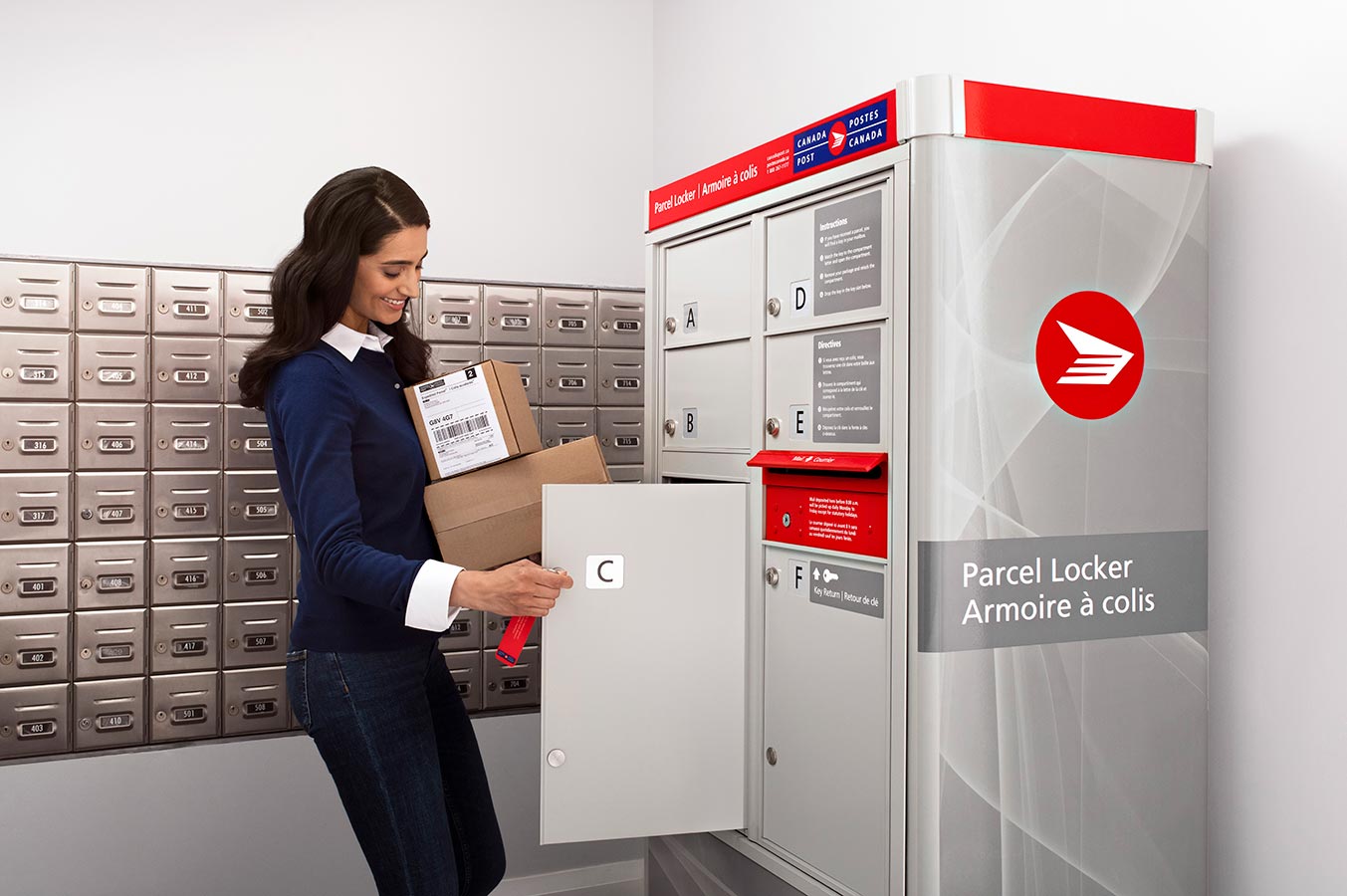 Woman picking up packages from her mailroom’s Canada Post parcel locker