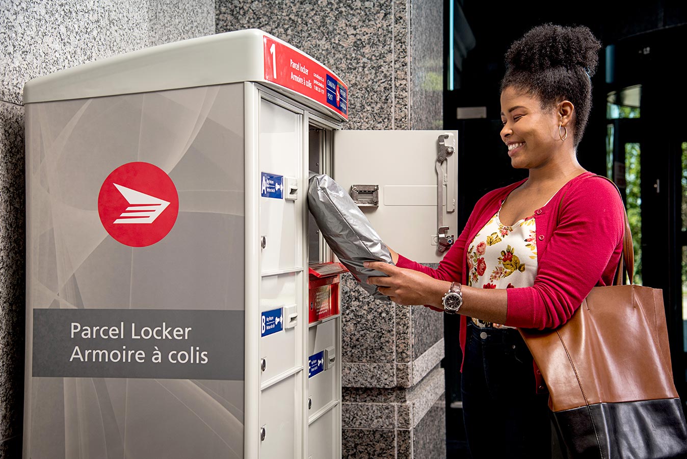 Woman picking up a package from a Canada Post parcel locker in her building