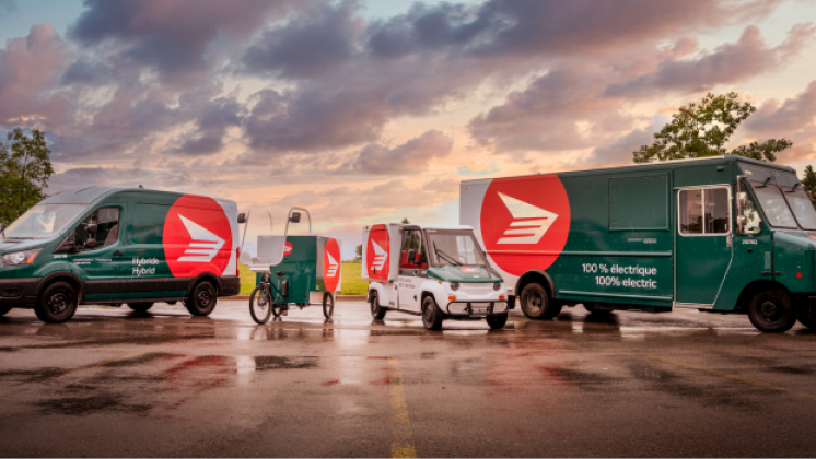 Canada Post hybrid and electric delivery vehicles parked in a row.