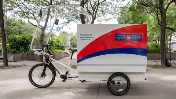 Un vélo avec remorque de Postes Canada utilisé comme véhicule de livraison écologique.