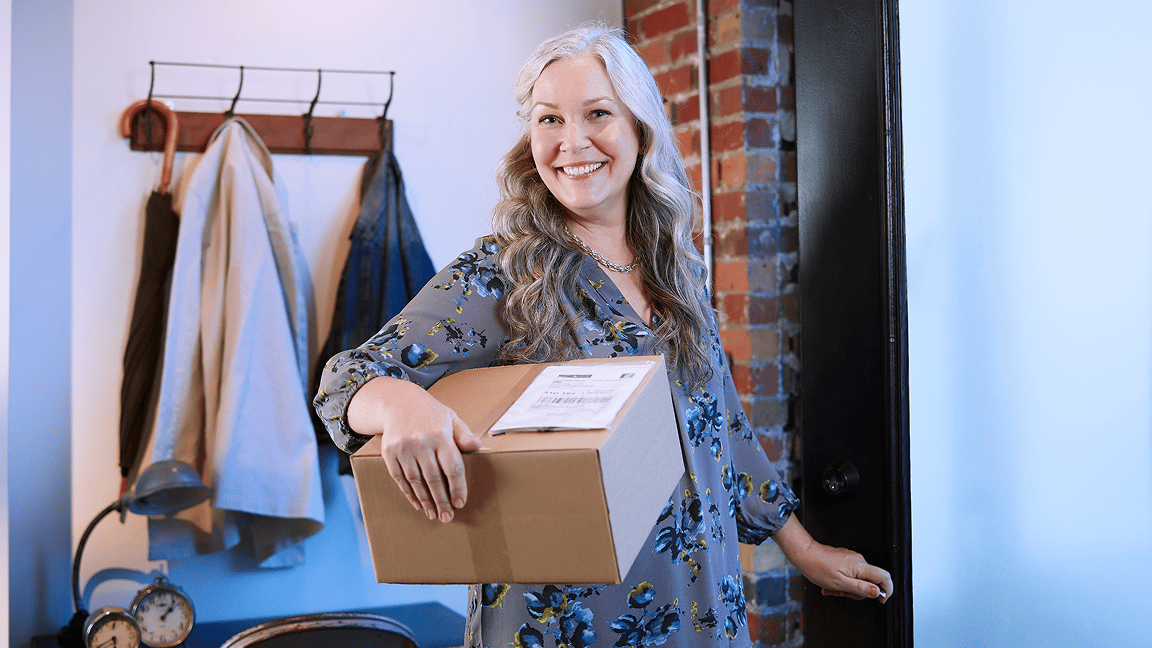 Photo of smiling woman holding a medium-size package that is ready for Home Pickup.