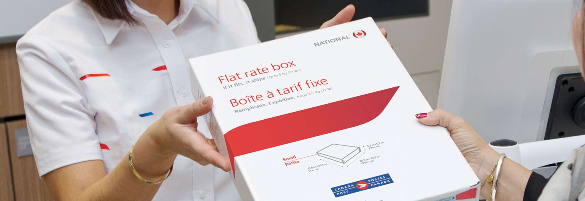 A woman buys a Canada Post flat rate box at a post office counter.