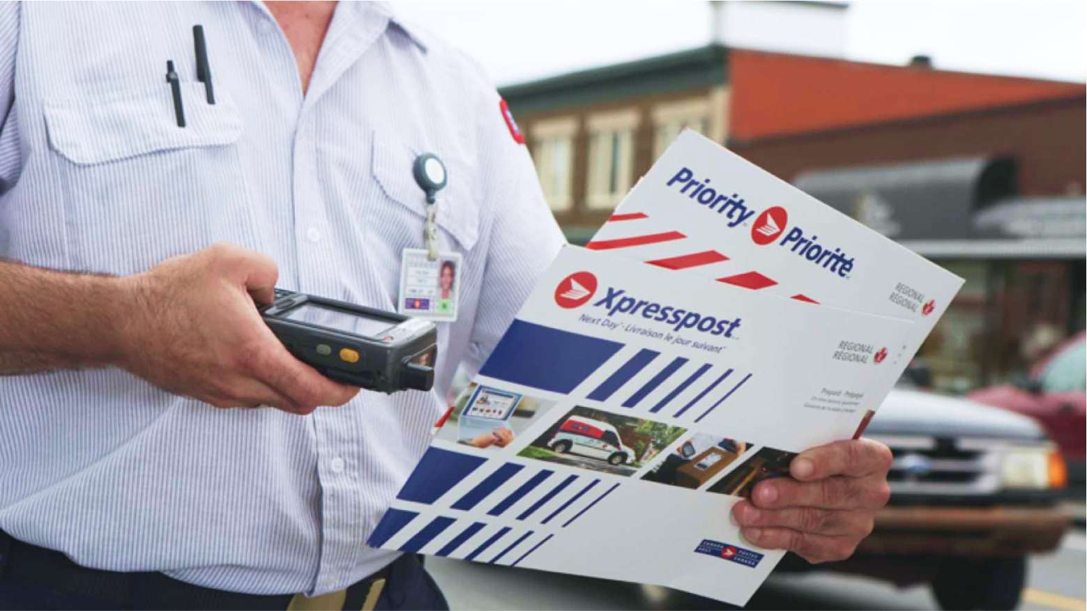 A Canada Post letter carrier scans two Xpresspost prepaid envelopes to update their tracking information.