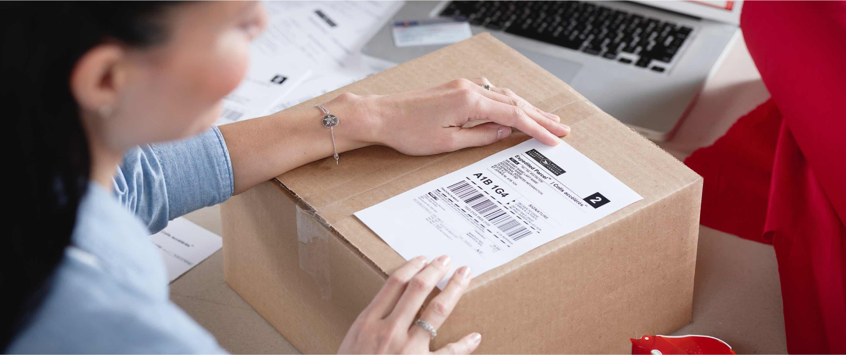 Woman applies a Canada Post return label to a package