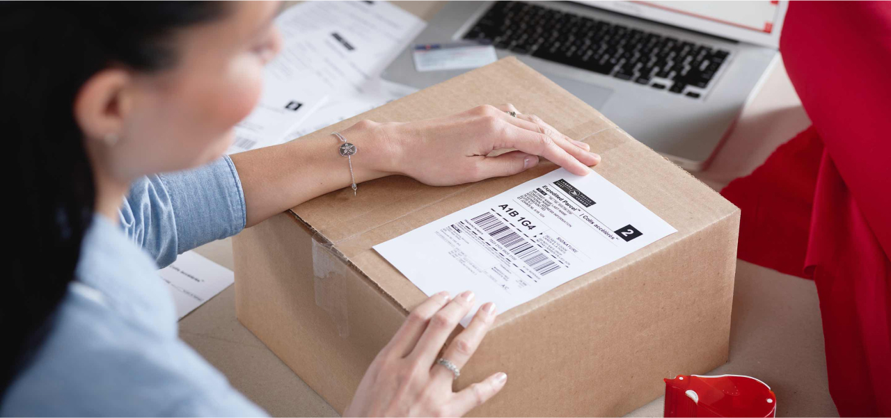 Woman applies a Canada Post return label to a package