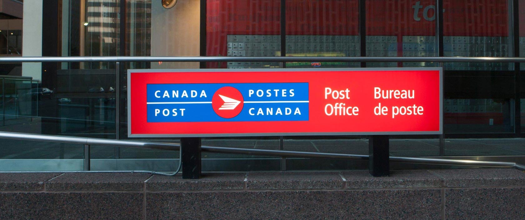Gros plan d’une grande enseigne affichant le logo bilingue de Postes Canada