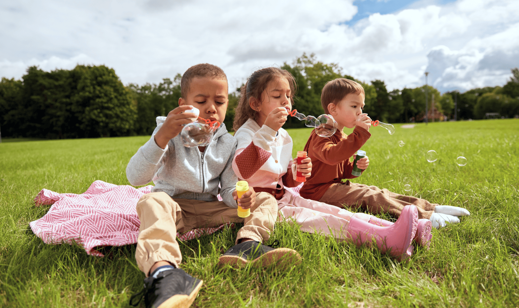 Des enfants heureux jouent dehors en faisant des bulles.