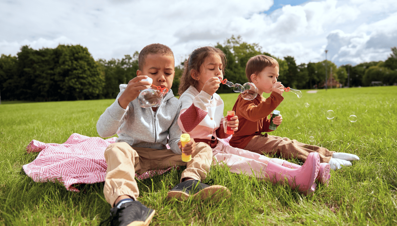Des enfants heureux jouent dehors en faisant des bulles.
