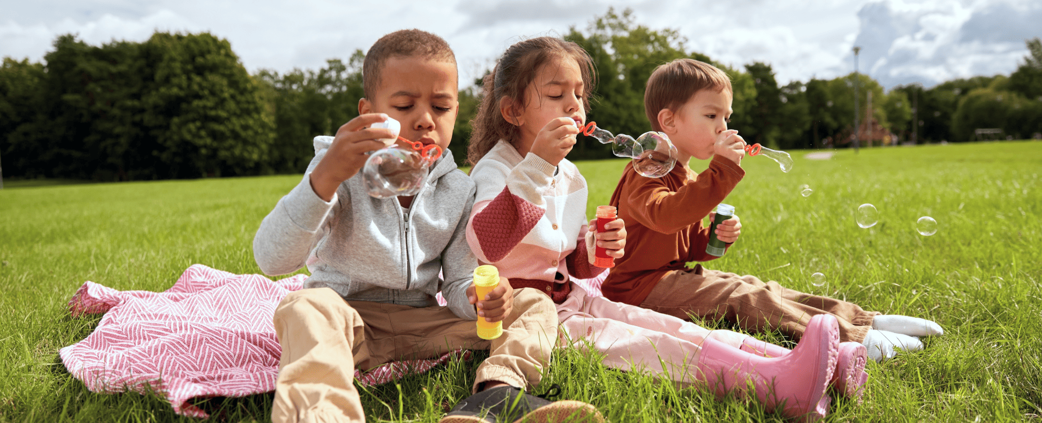 Des enfants heureux jouent dehors en faisant des bulles.