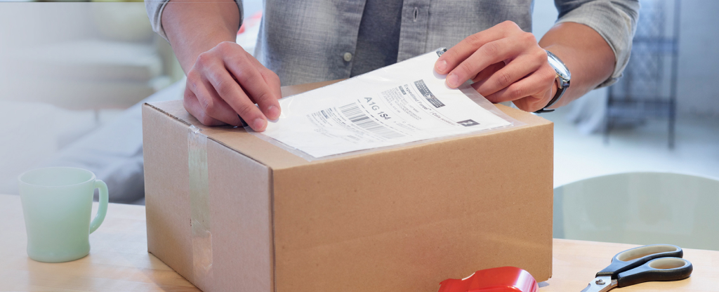 Un homme colle une étiquette d’expédition sur une boîte en carton
