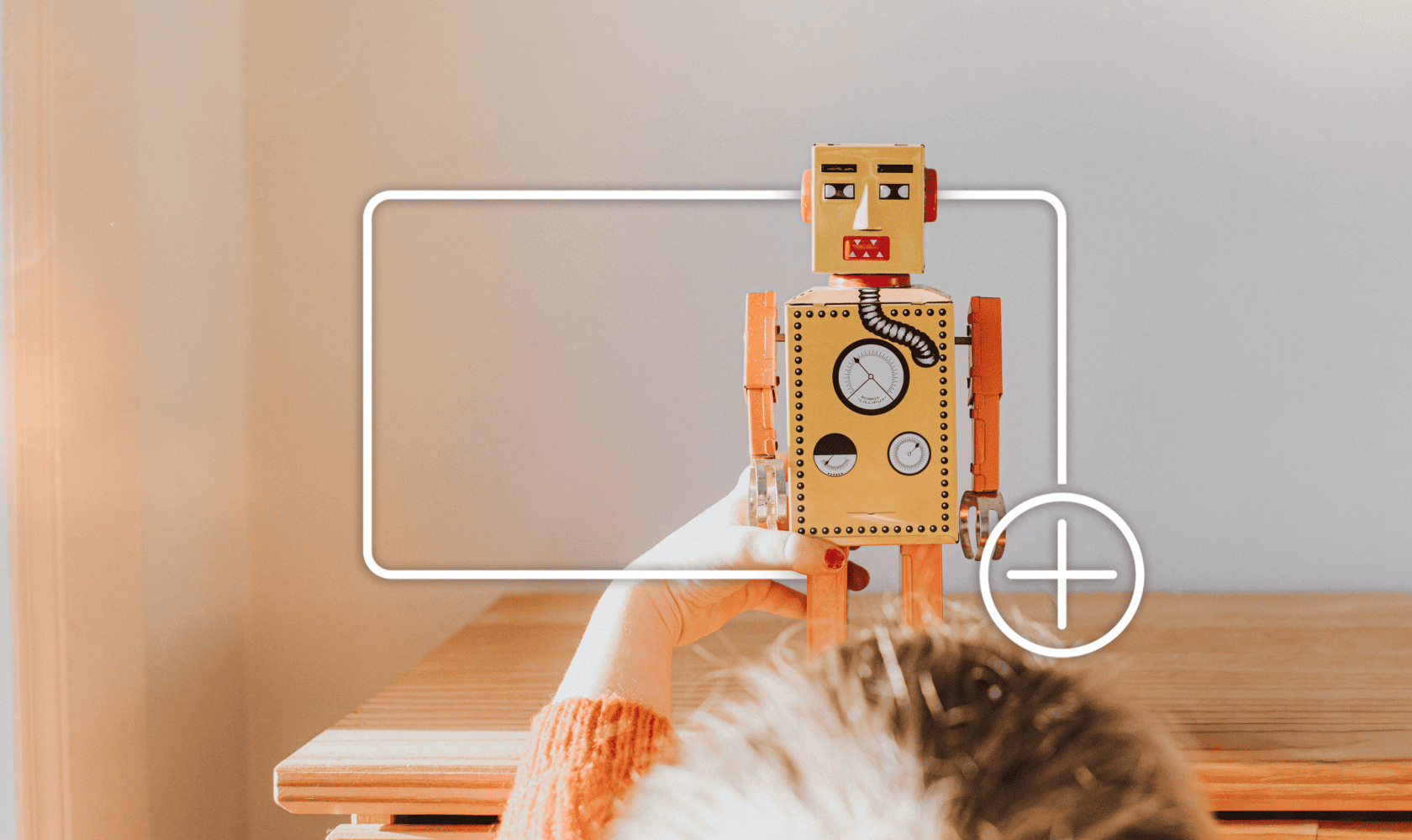 Un enfant joue avec un robot jouet, encadré d’une boîte blanche avec une icône « plus », indiquant qu’il est possible d’ajouter un article à un panier d’achats en ligne.
