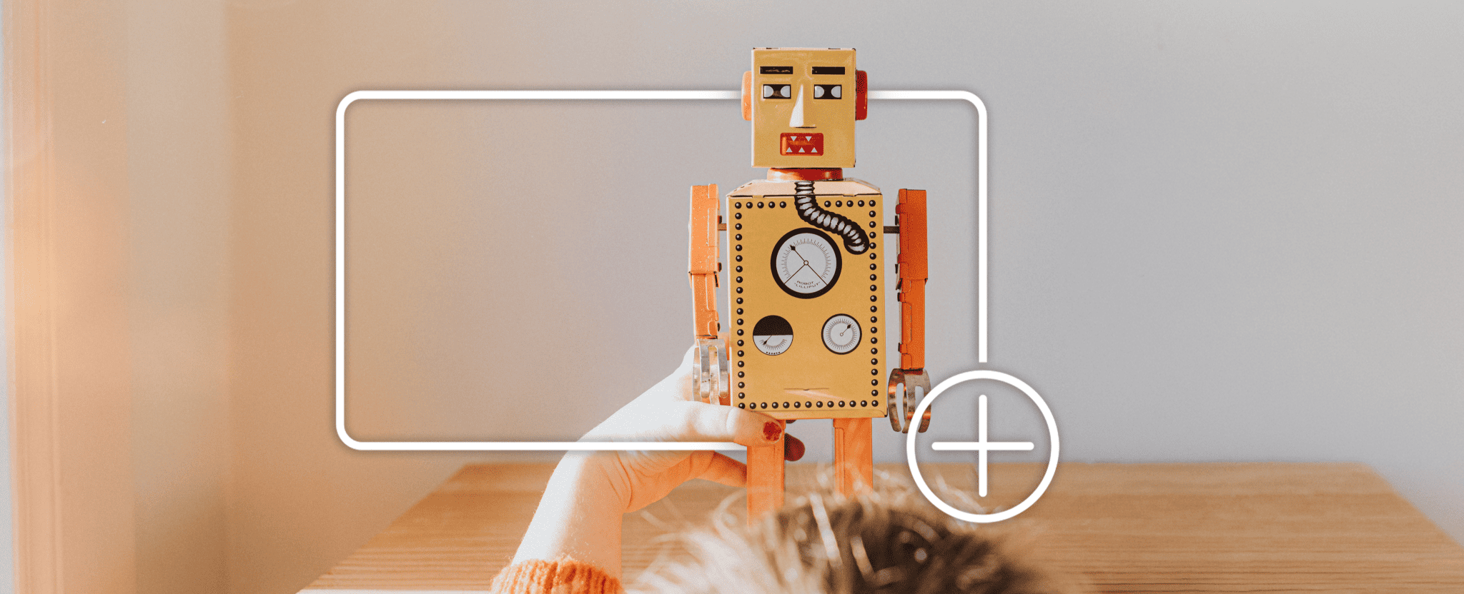 Un enfant joue avec un robot jouet, encadré d’une boîte blanche avec une icône « plus », indiquant qu’il est possible d’ajouter un article à un panier d’achats en ligne.