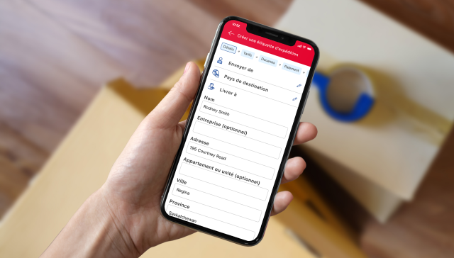 Un téléphone intelligent affiche l’écran de création d’étiquette de l’application de Postes Canada avec les champs de l’expéditeur, du pays de destination et de l’adresse.