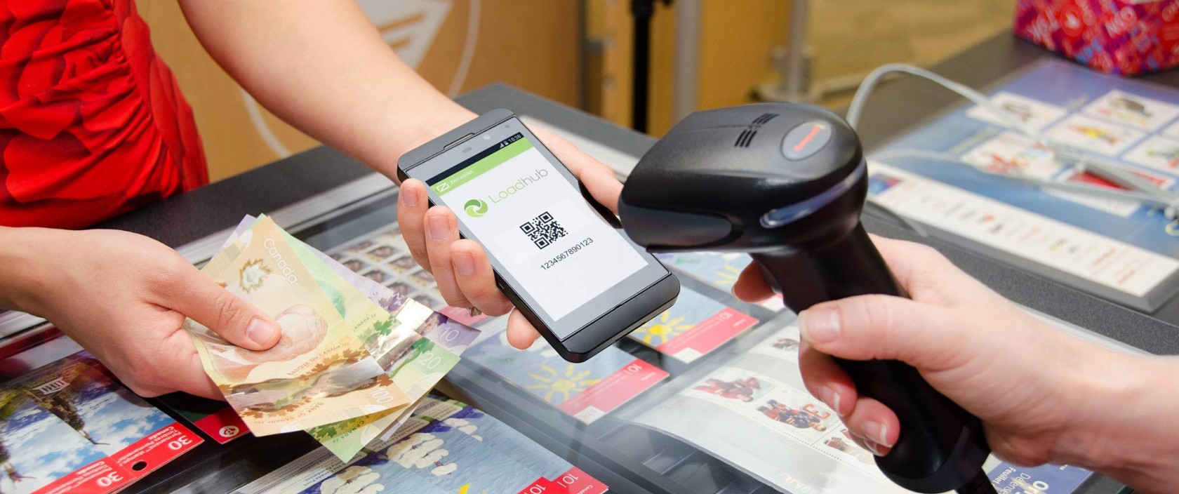 Une femme effectue un paiement en espèces et présente son code QR Loadhub à un comptoir de Postes Canada