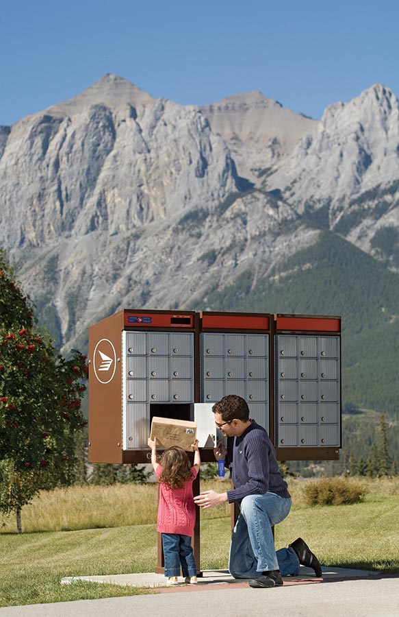 Un père et un enfant récupèrent un colis dans une boîte postale communautaire