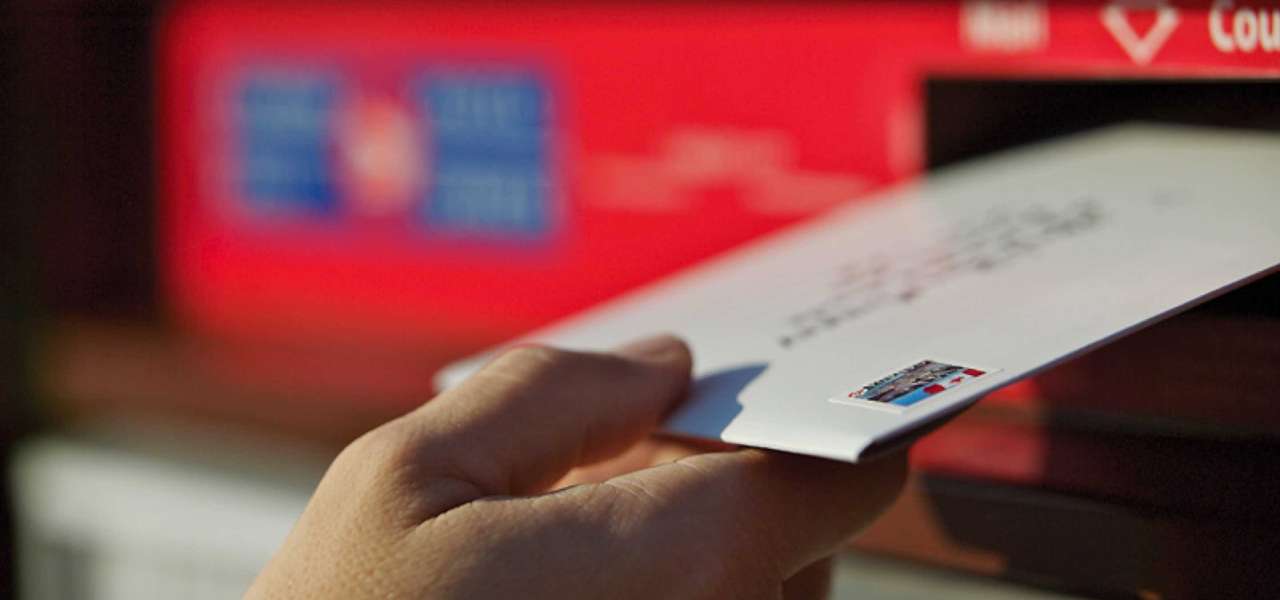 Une enveloppe prête pour l’expédition est déposée dans une boîte postale communautaire de Postes Canada