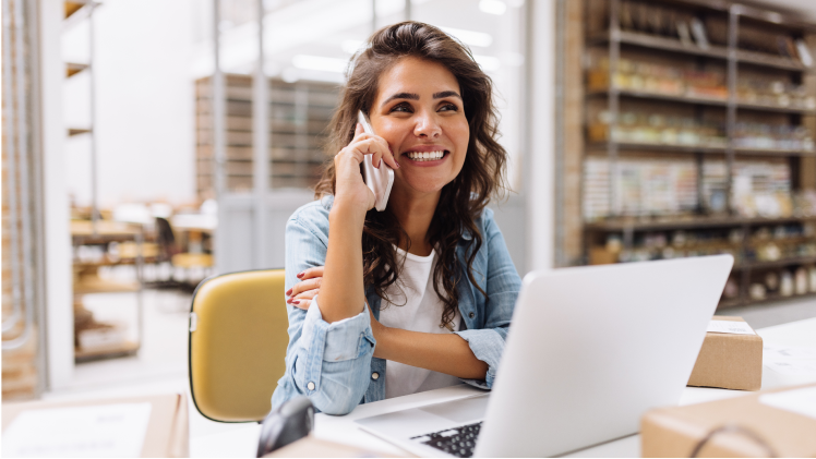 Une femme assise à un bureau devant un ordinateur portable parle sur un téléphone cellulaire. Une femme assise à un bureau devant un ordinateur portable parle sur un téléphone cellulaire.