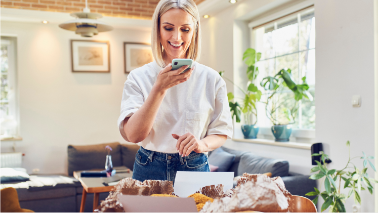 Une femme sourit en utilisant un téléphone cellulaire dans son salon. Une femme sourit en utilisant un téléphone cellulaire dans son salon.